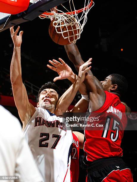 Zaza Pachulia of the Atlanta Hawks draws a foul while driving against Rasho Nesterovic and Amir Johnson of the Toronto Raptors at Philips Arena on...