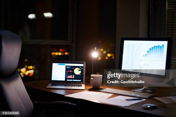 laptop and computer on office desk at night - laptop on desk no people stock pictures, royalty-free photos & images