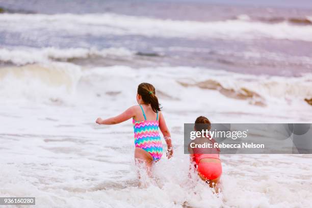 two girls playing in ocean waves, rear view, dauphin island, alabama, usa - alabama lifestyles stock pictures, royalty-free photos & images