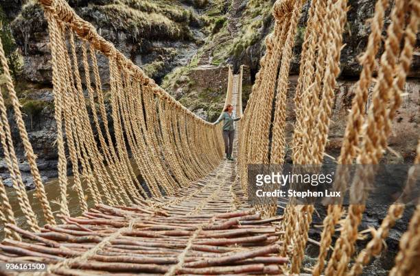 female tourist crossing inca rope bridge, huinchiri, cusco, peru - rope bridge stock pictures, royalty-free photos & images