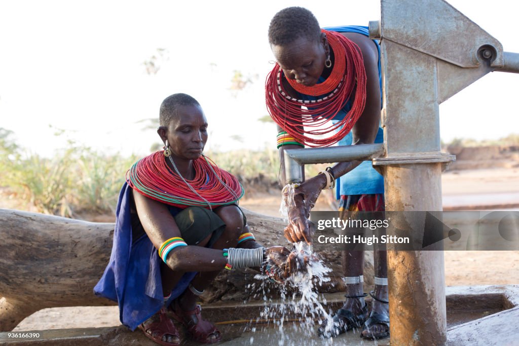 Women collecting clean water from borehole in desert. Samburu. Kenya.