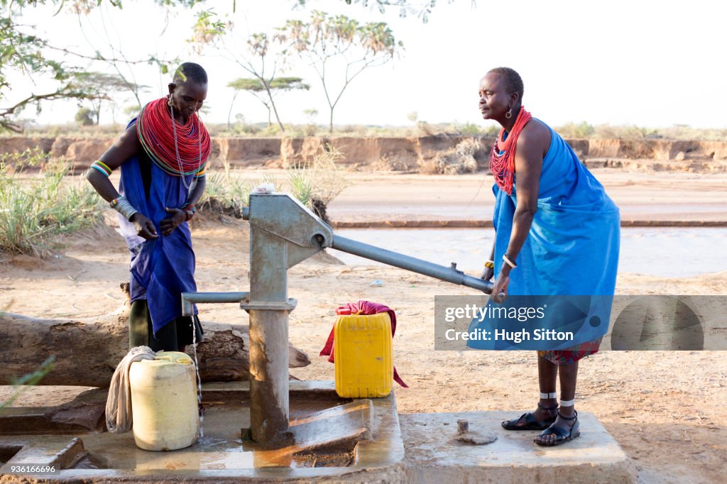 Women collecting clean water from borehole in desert. Samburu. Kenya.