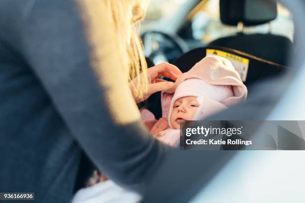 mother fastening young baby in car seat, mid section - fastening stock pictures, royalty-free photos & images