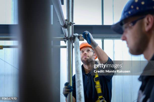 apprentice engineers preparing and setting up scaffolding - baugerüst stock-fotos und bilder