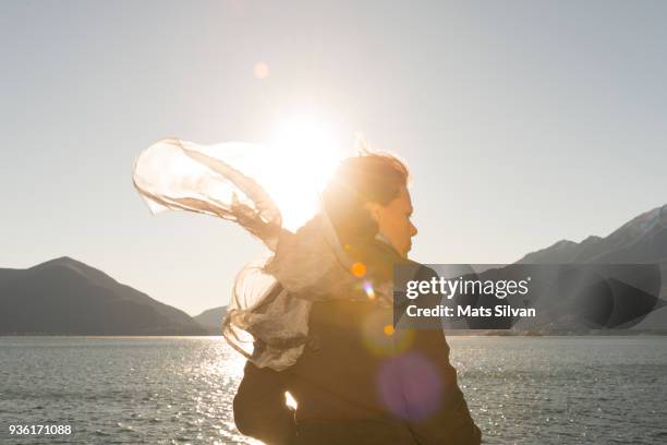 woman with moving hair and scarf in sunlight in a windy day - sun on face stock pictures, royalty-free photos & images