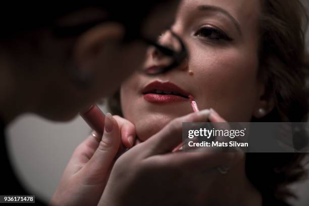 smiling beautiful woman putting on lipstick - retro hair salon stock pictures, royalty-free photos & images