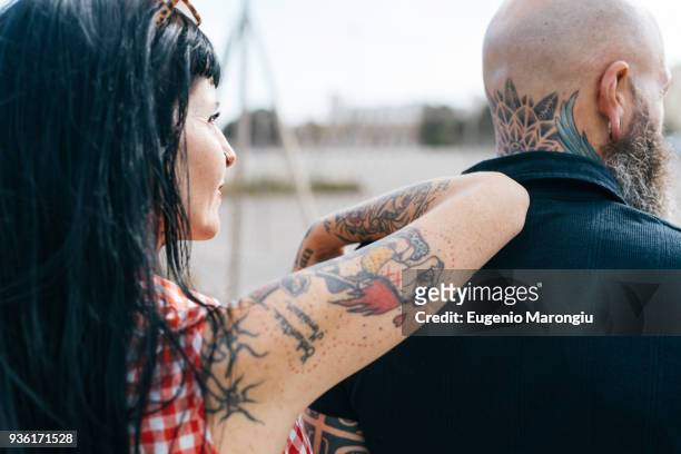 mature tattooed hipster woman leaning on boyfriends shoulder - tattoo shoulder stock-fotos und bilder
