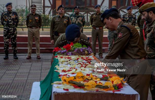 An Indian police officer lays wreath on the coffin containing the body of his comrade, Deepak Thusoo, killed in a gun battle with suspected rebels,...