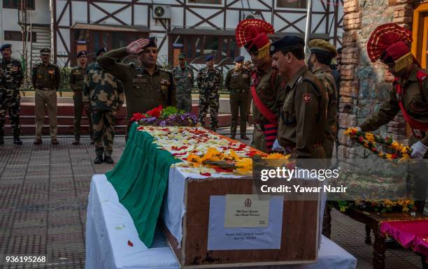 An Indian police officer salutes the coffin containing the body of his comrade, Deepak Thusoo, killed in a gun battle with suspected rebels, during...