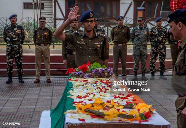 An Indian police officer salutes the coffin containing the body of his comrade, Deepak Thusoo, killed in a gun battle with suspected rebels, during...