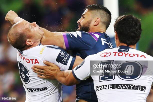 Matthew Scott of the Cowboys tries to tackles Jesse Bromwich of the Storm who collects him high during the round three NRL match between the...