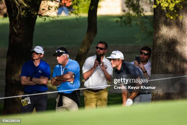 Keegan Bradley watches his punch shot after his tee shot went outside the ropes on the 18th hole fairway during round one of the World Golf...