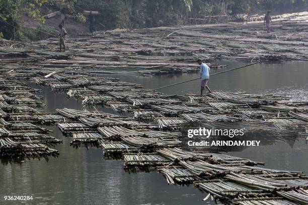 Indian labourers push heaps of bamboo on a river to be sold at a floating market -- and set to be used in the construction industry -- in Chakmaghat,...