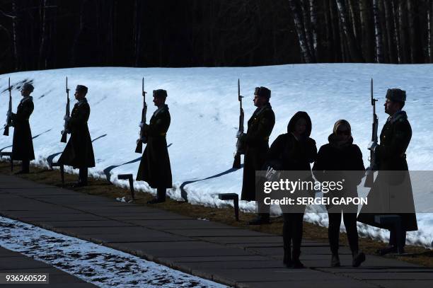 Women walk past honour guards at the monument to the residents of the Belarus village of Khatyn burnt alive in 1943 by the Nazis with participation...