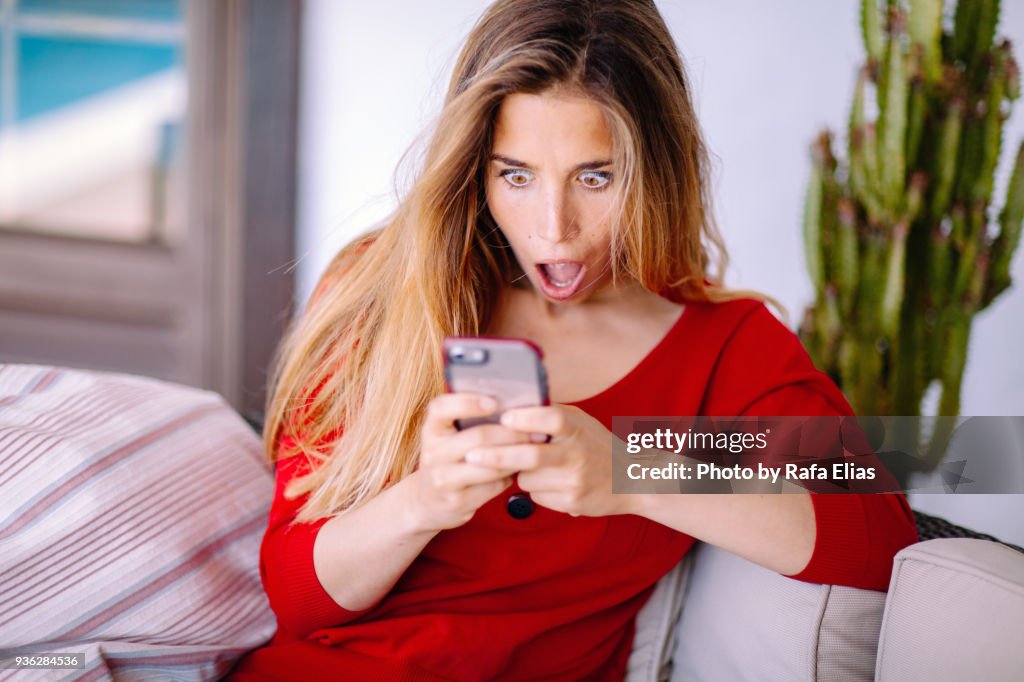 Woman feeling big surprise checking phone