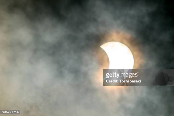 solar eclipse in new york u.s.a. on aug. 21 2017. the crescent shaped sun glows from among the moving clouds. - solar eclipse in new york stock pictures, royalty-free photos & images
