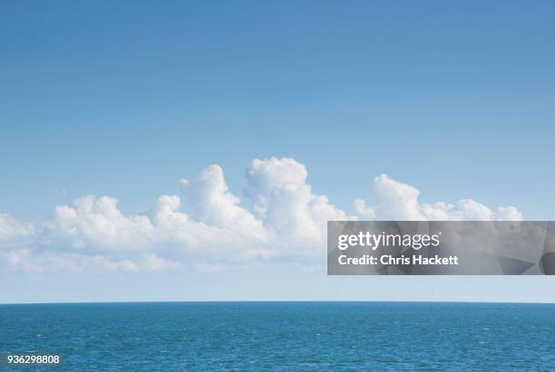 white cumulus clouds above blue atlantic ocean - cumulus stockfoto's en -beelden