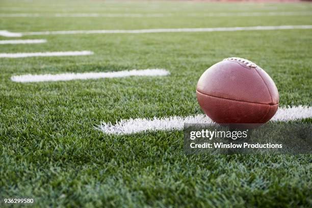 close up of american football ball on green playing field - american football pitch stock-fotos und bilder