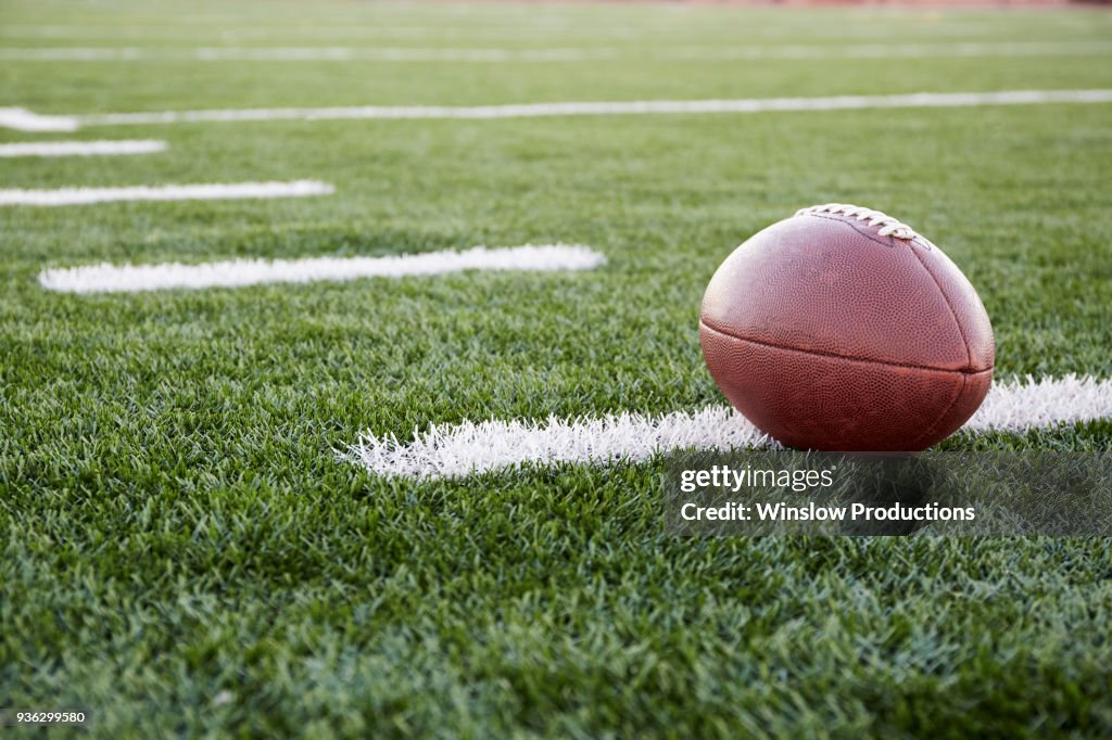 Close up of American football ball on green playing field