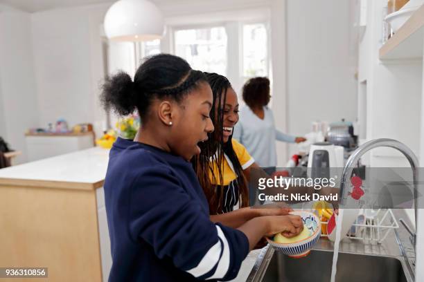 two teenage girls (12-13, 14-15) washing dishes - girls taking a showering stockfoto's en -beelden