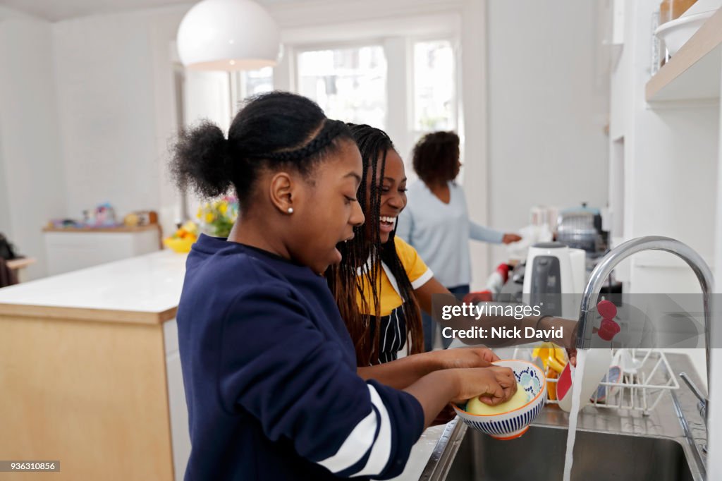 Two teenage girls (12-13, 14-15) washing dishes