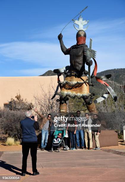 Visitors take souvenir photographs in front of a bronze sculpture depicting an Apache Mountain Spirit Dancer, by Craig Dan Goseyun, in the plaza of...