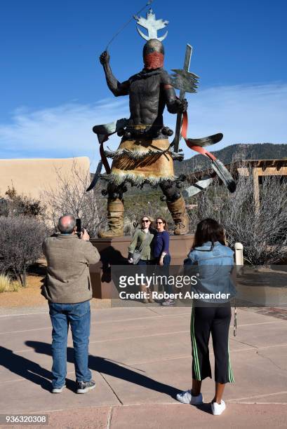 Visitors take souvenir photographs in front of a bronze sculpture depicting an Apache Mountain Spirit Dancer, by Craig Dan Goseyun, in the plaza of...