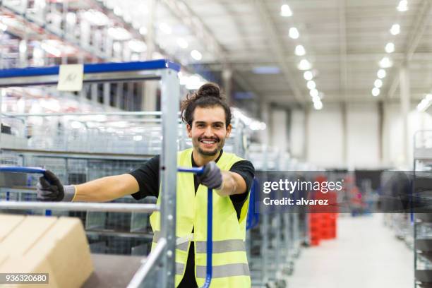 Male worker moving goods trolley in warehouse