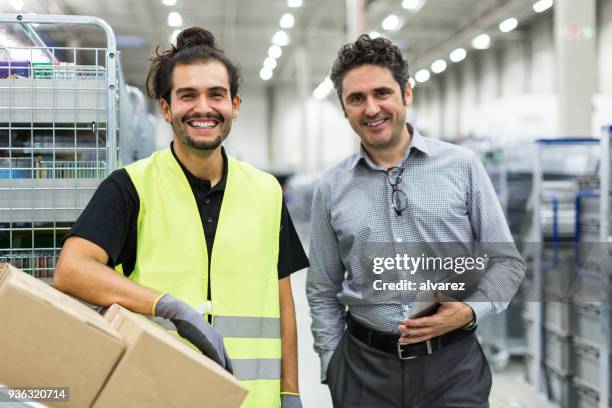 lächelnde lagerarbeiter mit vorarbeiter - büroangestellter stock-fotos und bilder