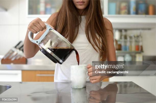 girl pouring a cup of coffee in the kitchen - fülle stock-fotos und bilder