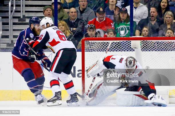 Erik Karlsson of the Ottawa Senators plays defense as Mike Condon of the Ottawa Senators attempts to block a shot by David Savard of the Columbus...
