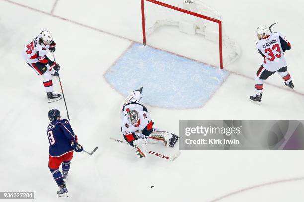 Mike Condon of the Ottawa Senators knocks the puck away from Zach Werenski of the Columbus Blue Jackets during the game on March 17, 2018 at...