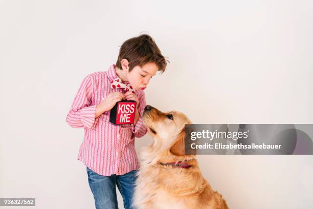 boy blowing a kiss to his golden retriever dog - mandare un bacio foto e immagini stock