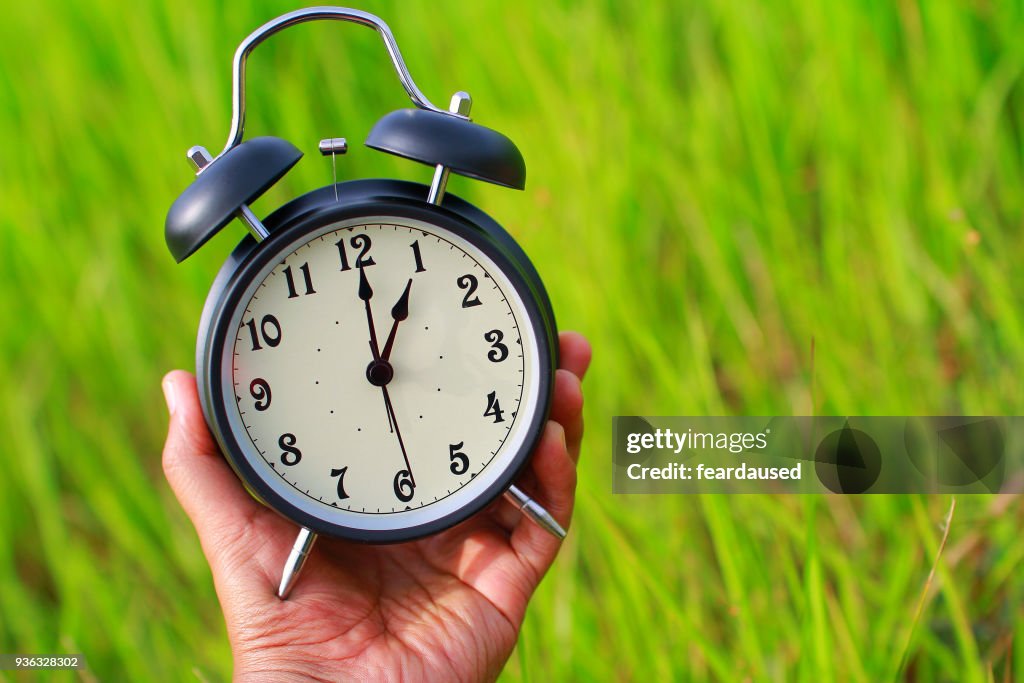 Human hand holding an alarm clock