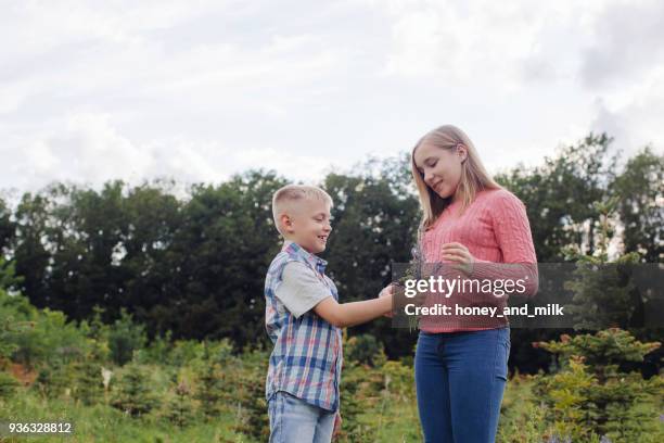 boy giving a girl freshly picked flowers in a meadow - honey boy fotografías e imágenes de stock