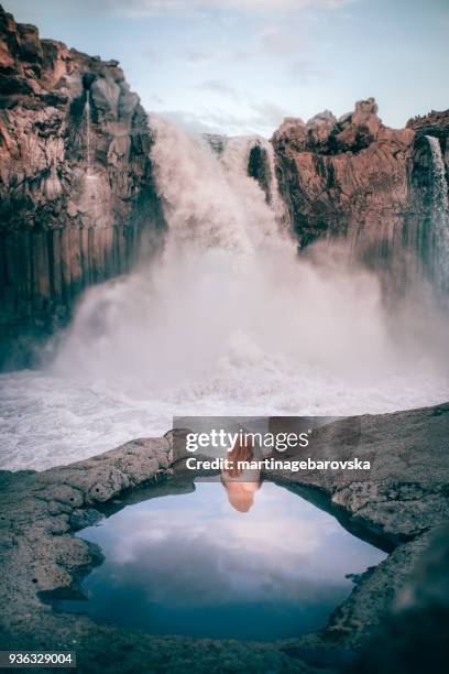 rear view of a woman in a rock pool looking at aldeyjarfoss waterfall, highlands, iceland - highlands-of-iceland stockfoto's en -beelden