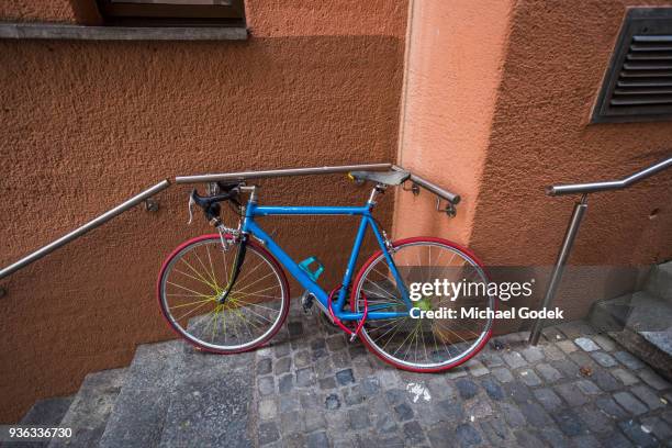 brightly colored bicycle parked against a building in central zurich - fahrradschloss stock-fotos und bilder