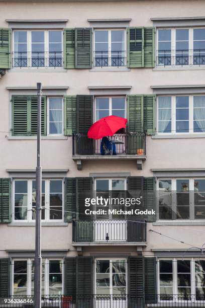 bright red umbrella on small balcony in zurich - window awnings stock-fotos und bilder
