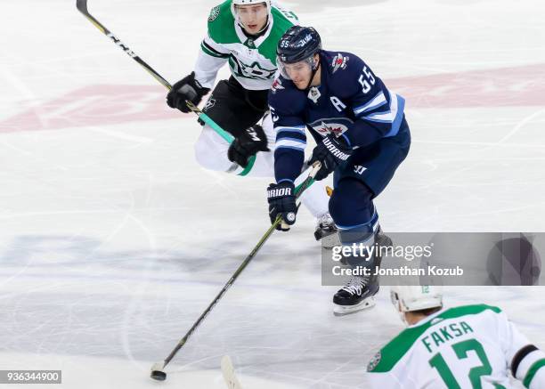 Mark Scheifele of the Winnipeg Jets plays the puck down the ice as Tyler Pitlick and Radek Faksa of the Dallas Stars look on during third period...