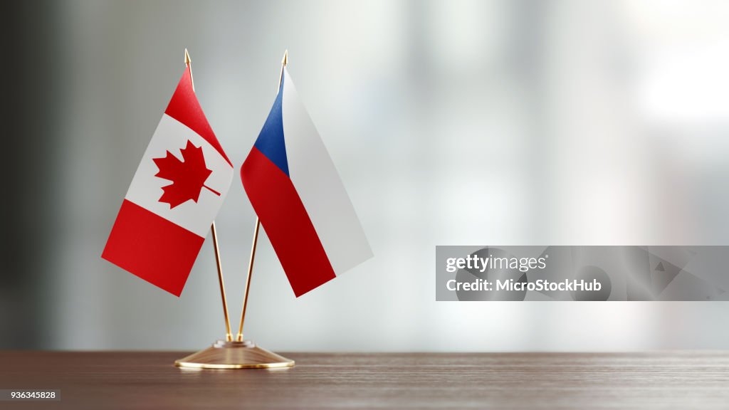 Coppia di bandiere canadesi e cecoslovagane su una scrivania su sfondo sfocato