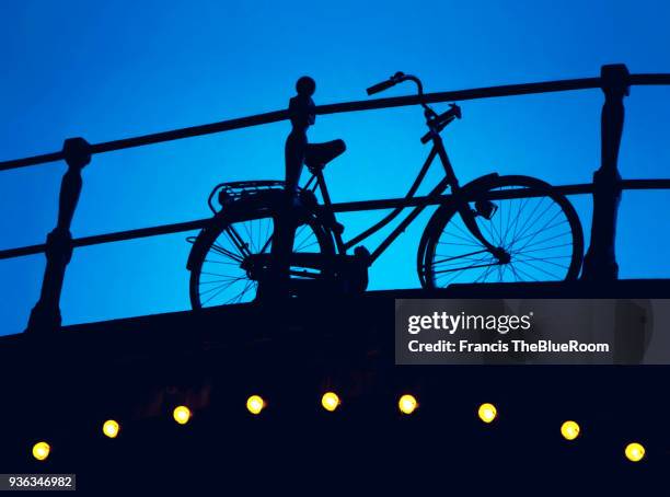 silhouette of a bicycle on a bridge in amsterdam - amsterdam bike stock-fotos und bilder