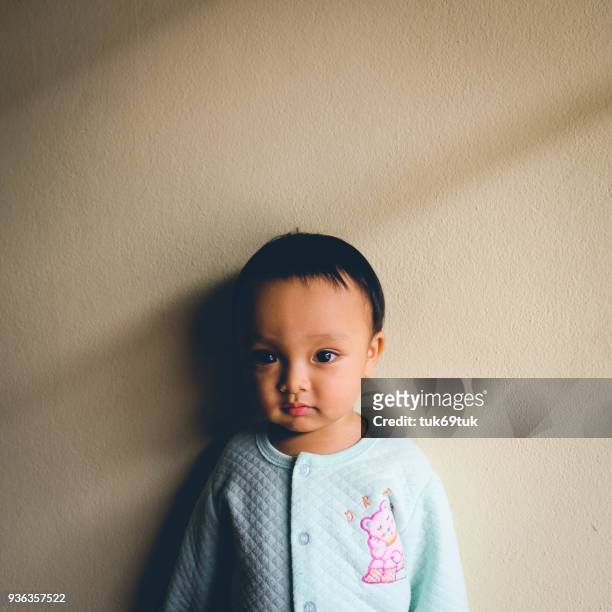 Close-Up Portrait Of Baby Boy Standing By Beige Wall