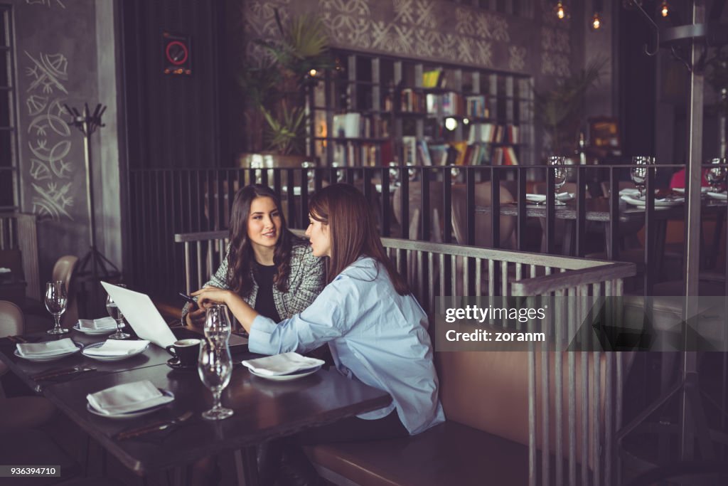 Coworkers in restaurant, using laptop