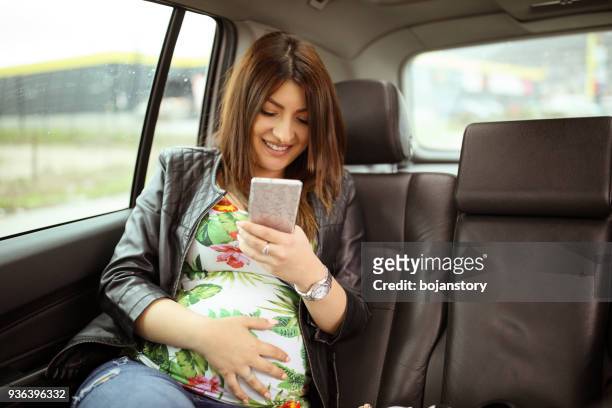 pregnant woman using mobile in car - pregnant woman car stock pictures, royalty-free photos & images