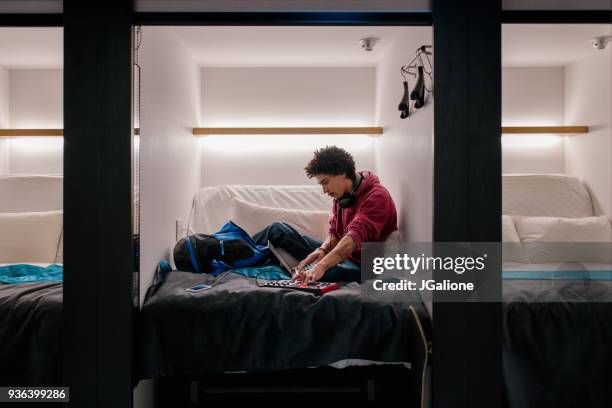 young adult male using audio equipment in a capsule hotel - claustrophobia stock pictures, royalty-free photos & images