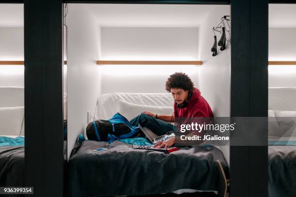 young adult male using audio equipment in a capsule hotel - capsule hotel stock pictures, royalty-free photos & images