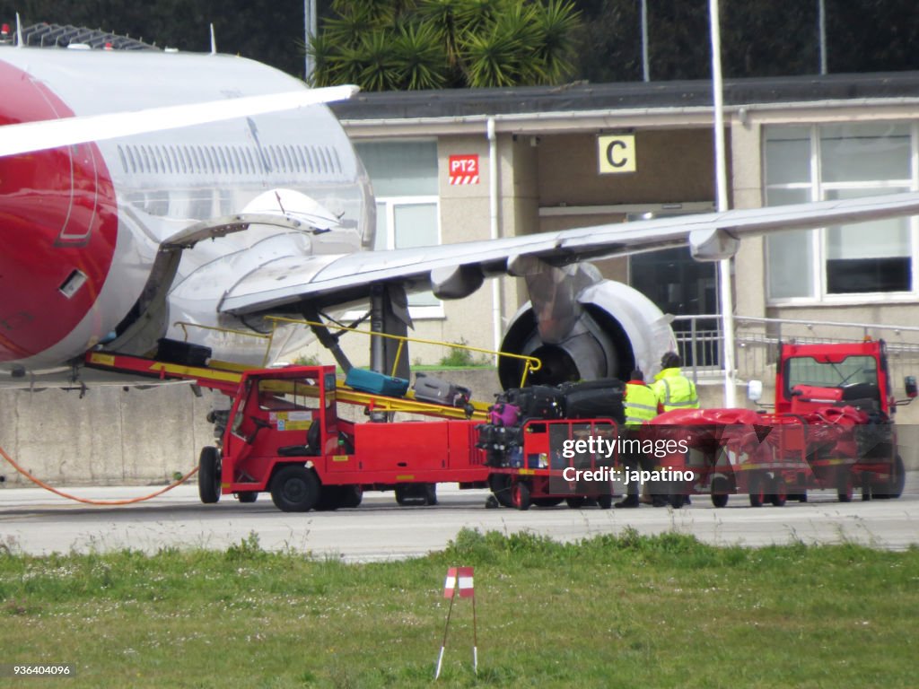 Ground staff unloading suitcases from a commercial plane