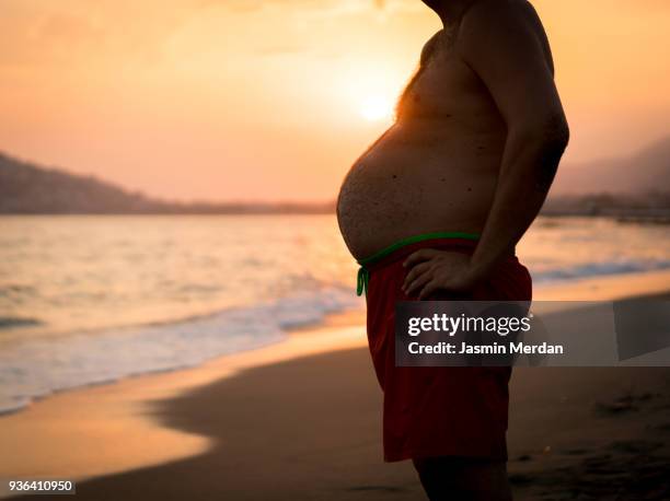 fat man with big stomach - fat man on beach stockfoto's en -beelden