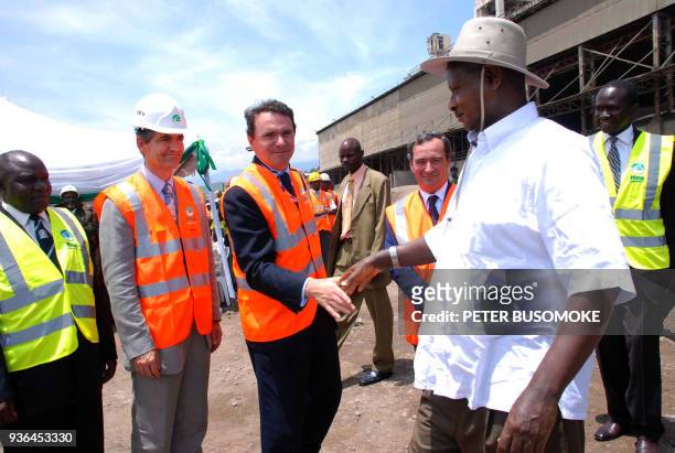 Ugandan President Yoweri Museveni greets the head of France's construction material company Lafarge, Bruno Lafont upon Museveni's arrival to the...