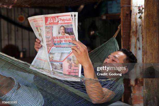 Man reading newspaper in a Hammock. Vietnam.